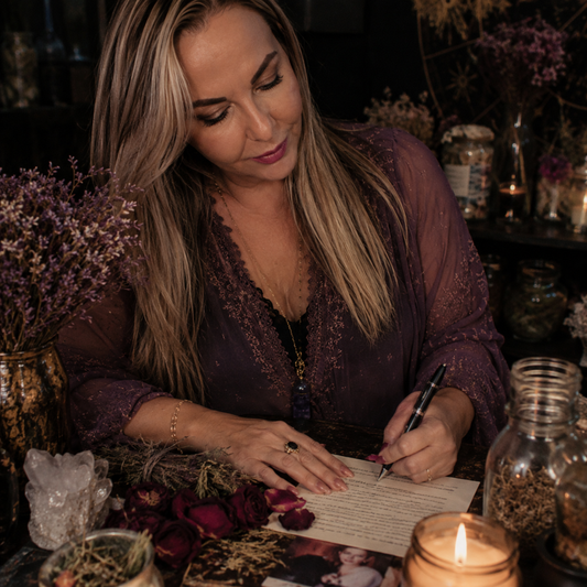 Belinda preparing a private regret spell with candles, herbs, crystals, and petition paper for emotional reflection and closure.