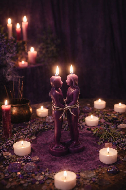 Illustrative scene with two purple figure candles, tea lights, purple crystals, and incense