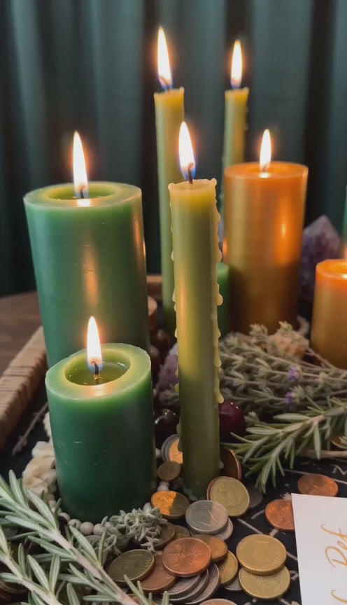 Belinda preparing a Debt Relief and Money Harmony Spell ritual with green and gold candles, coins, herbs, and a handwritten money intention petition.