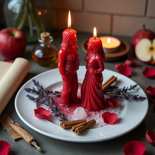 Load image into Gallery viewer, Two lit red figure candles facing each other on a plate with rose petals, lavender sprigs, cinnamon sticks, and a crystal for a Reuniting Love Spell ritual.