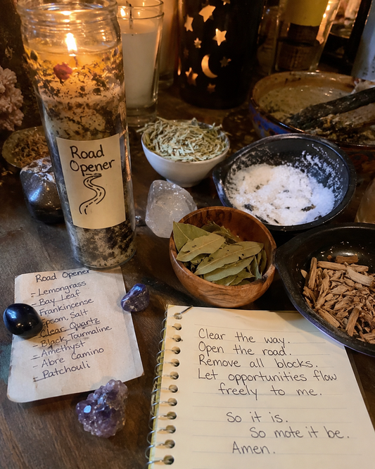 Close-up cellphone-style image of Road Opener Spell candles with herbs, salt, crystals, bay leaves, and ritual notes on a candlelit altar.